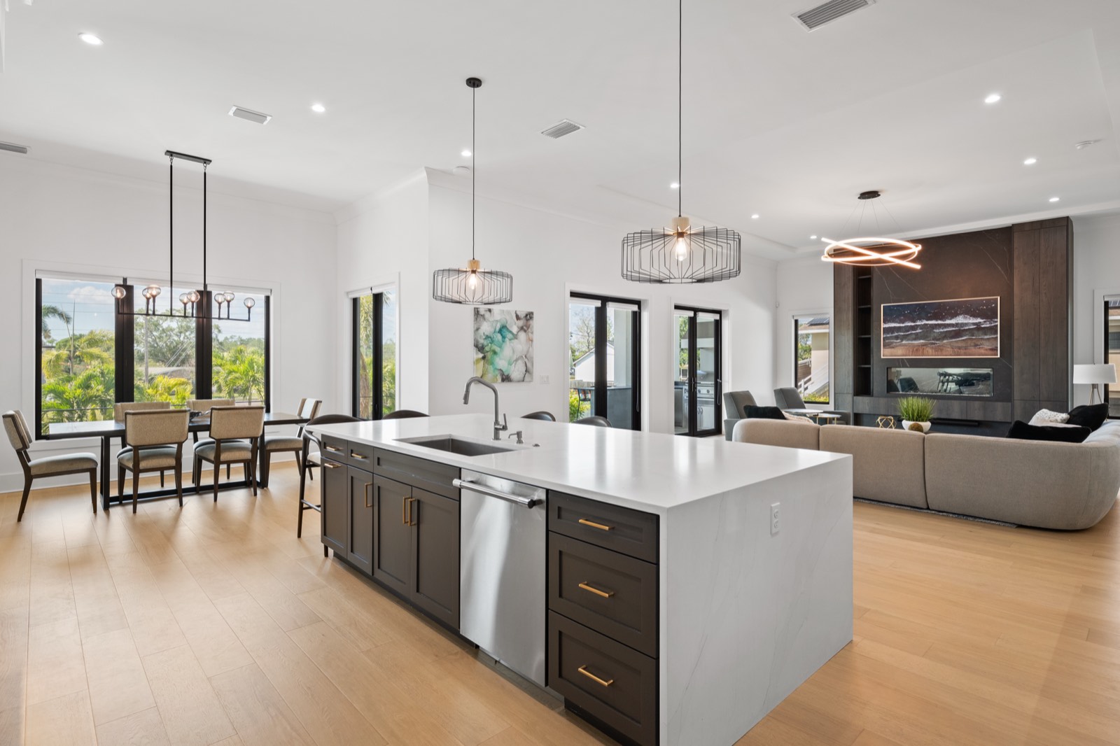 Open-plan kitchen and great room in a St. Petersburg new build, waterfall-edge island and linear fireplace beyond