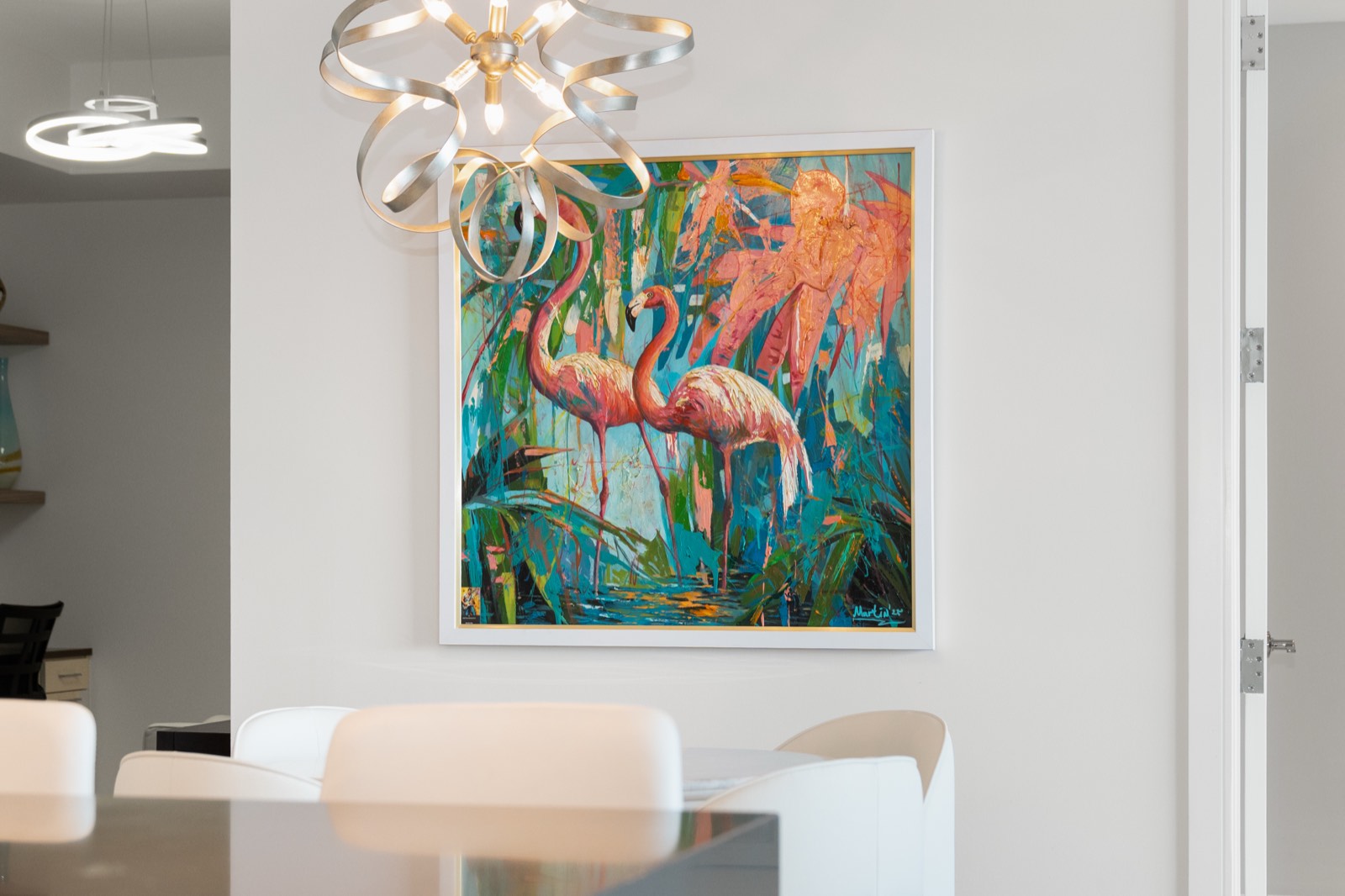 Framed flamingo painting and sculptural chandelier above a dining table in a Tampa Bay interior